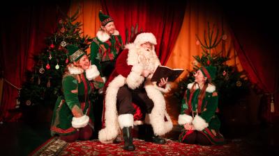 Father Christmas reading a book with his Elves